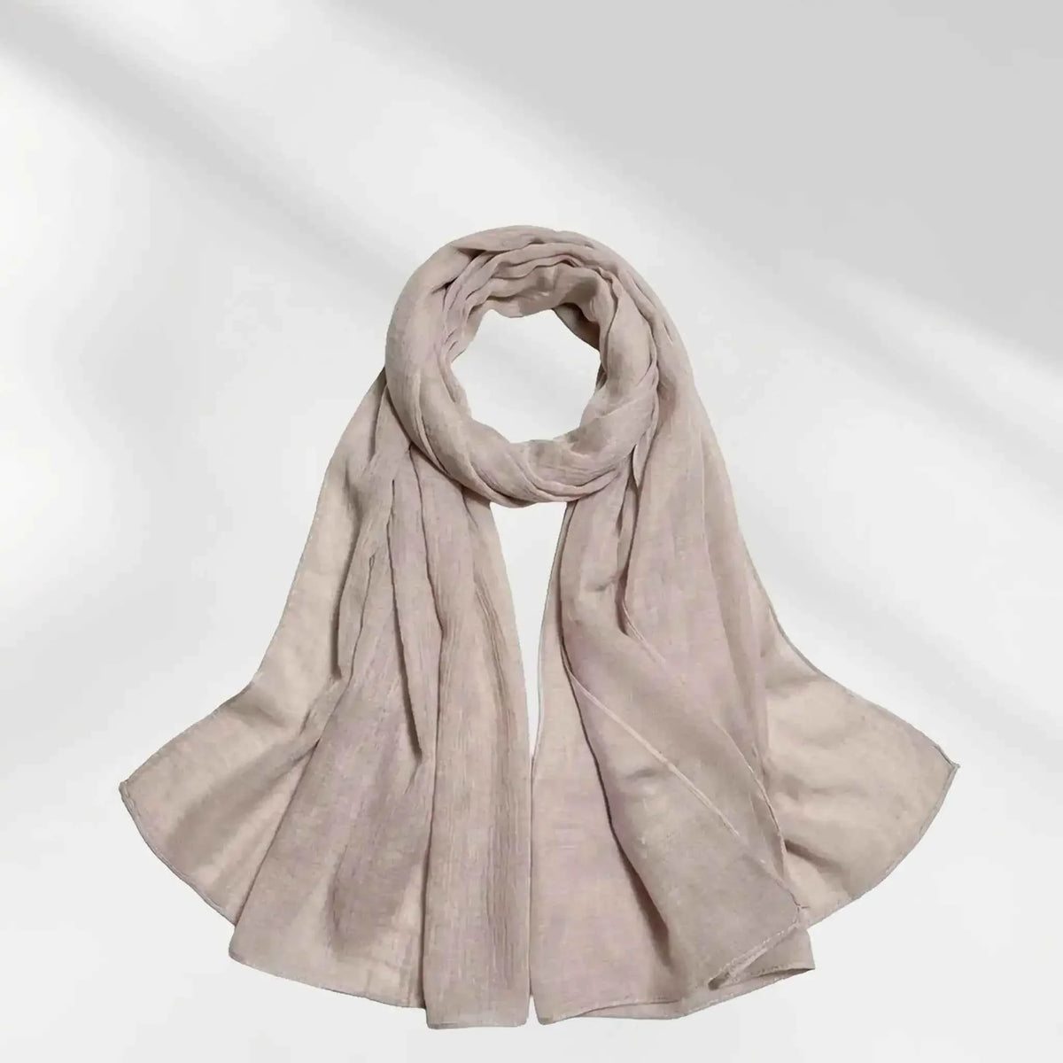 Beige modal hijab scarf coiled and draped on a white background, showing the fabric texture and drape