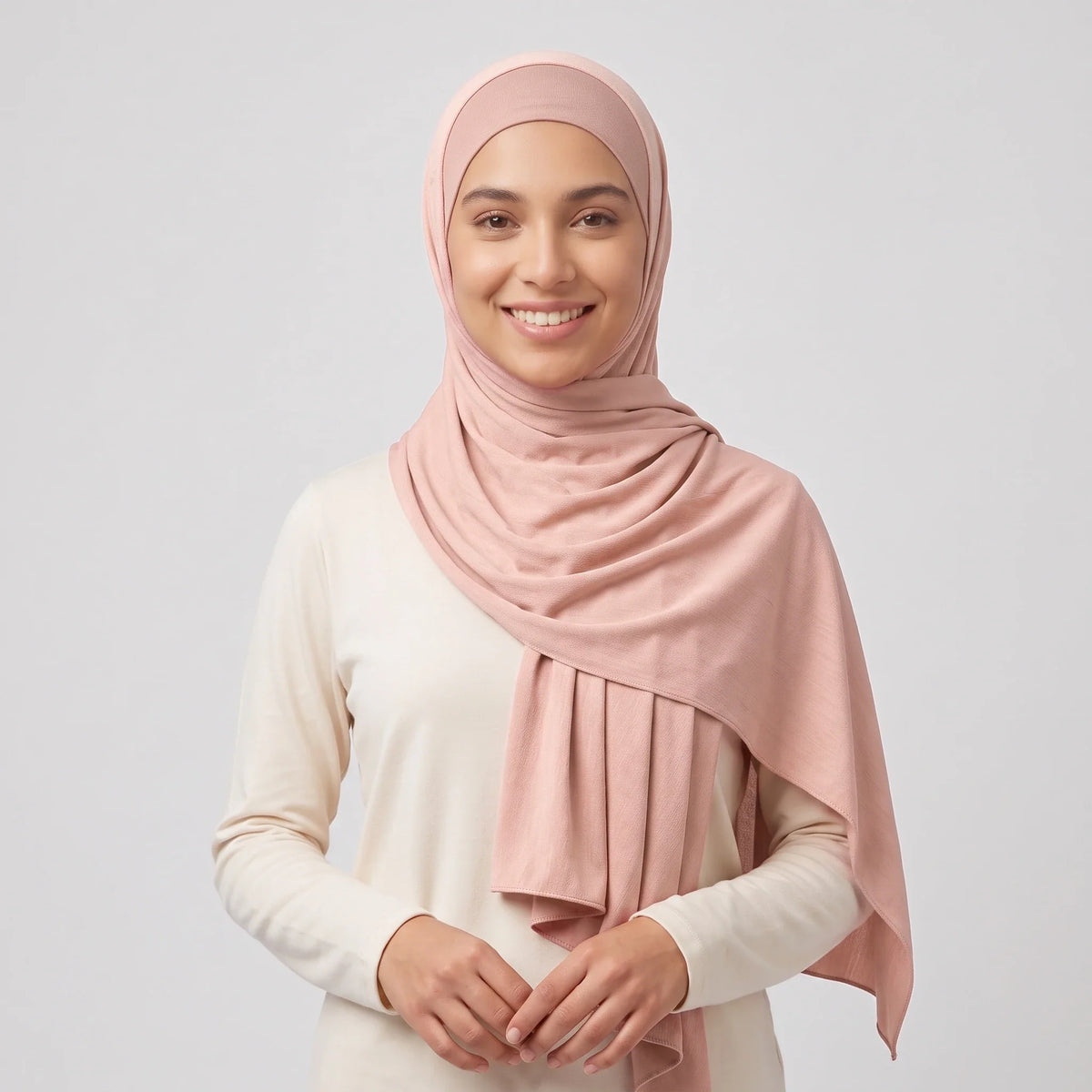 Woman wearing a light pink jersey hijab over a dusty pink hijab cap