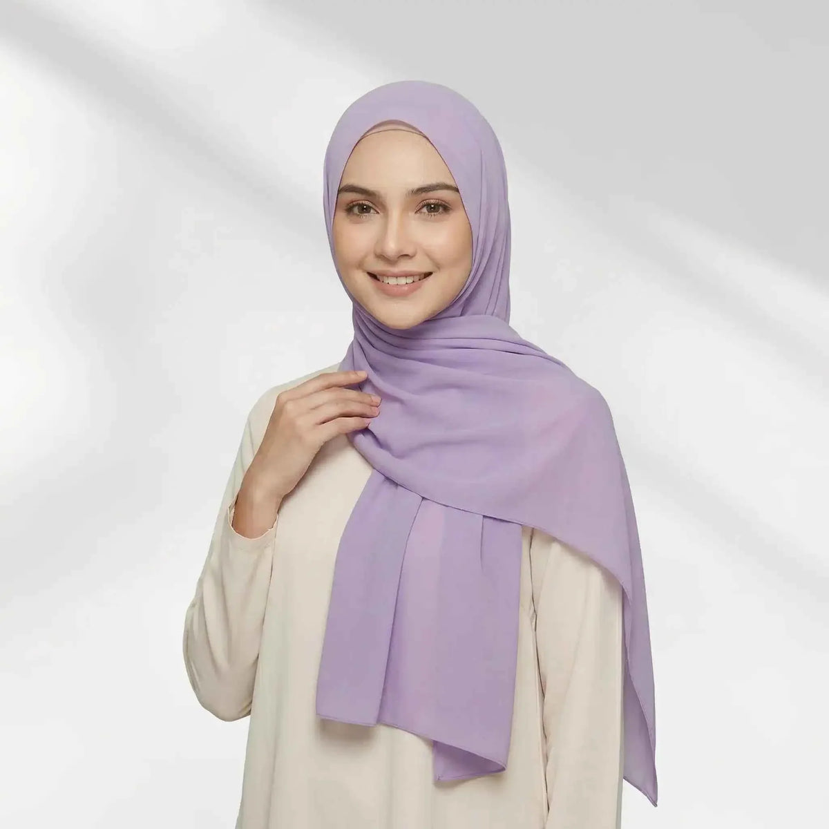 Woman wearing a purple chiffon hijab draped over one shoulder with a hijab undercap underneath