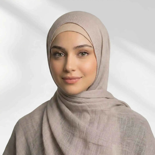 Woman wearing a beige modal hijab styled over the matching undercap, draped over both shoulders