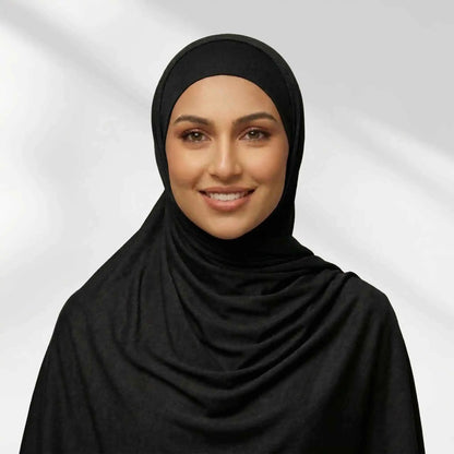 Woman wearing a black jersey hijab draped for full chest coverage, front view