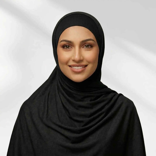 Woman wearing a black jersey hijab draped for full chest coverage, front view