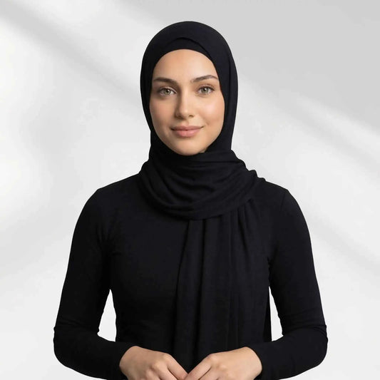 Woman wearing a black modal hijab wrapped and draped over one shoulder