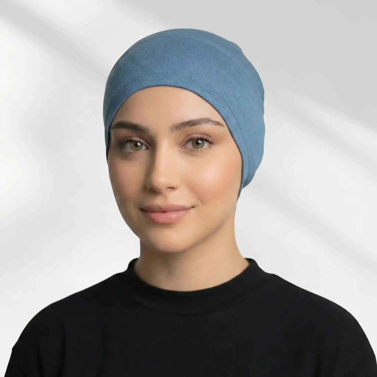 Woman wearing the blue hijab cap on its own, showing full hairline coverage