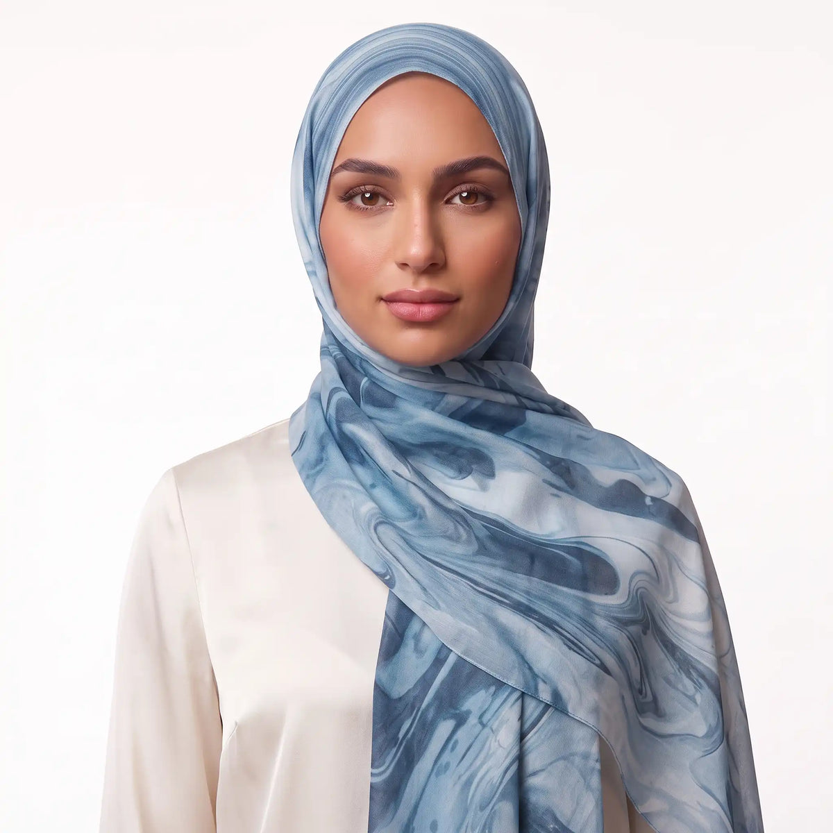 Woman wearing a blue modal hijab with a printed pattern over a cream top