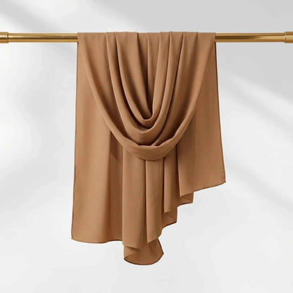 Brown chiffon hijab elegantly hanging and draped over a gold bar showing sheer fabric drape.