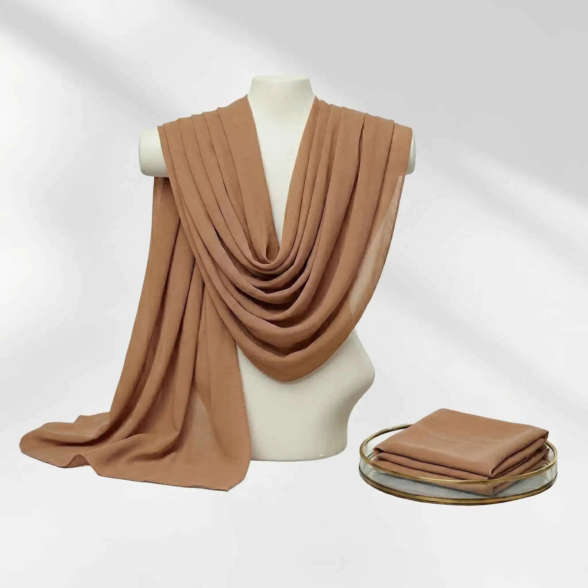 Brown chiffon hijab scarf gracefully draped on a mannequin bust with a matching folded hijab.