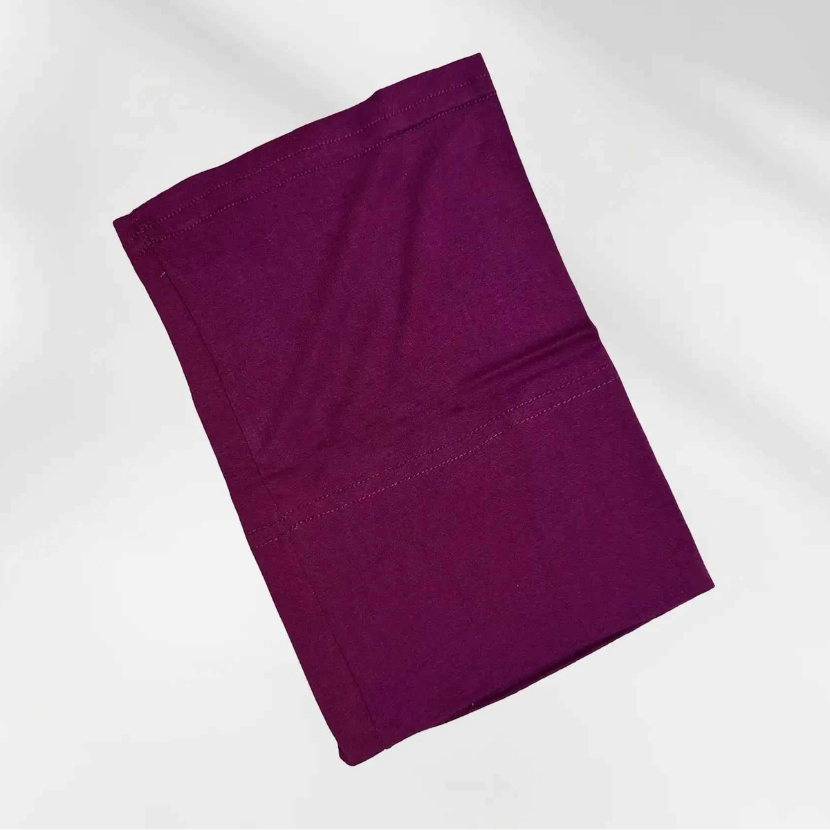 Burgundy hijab cap folded flat, showing the fitted shape and stitched edge that sits at the hairline