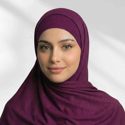Woman wearing a burgundy modal hijab draped over the matching hijab undercap
