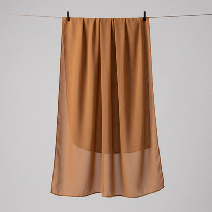 Gold chiffon hijab hanging full length, showing the lightweight drape