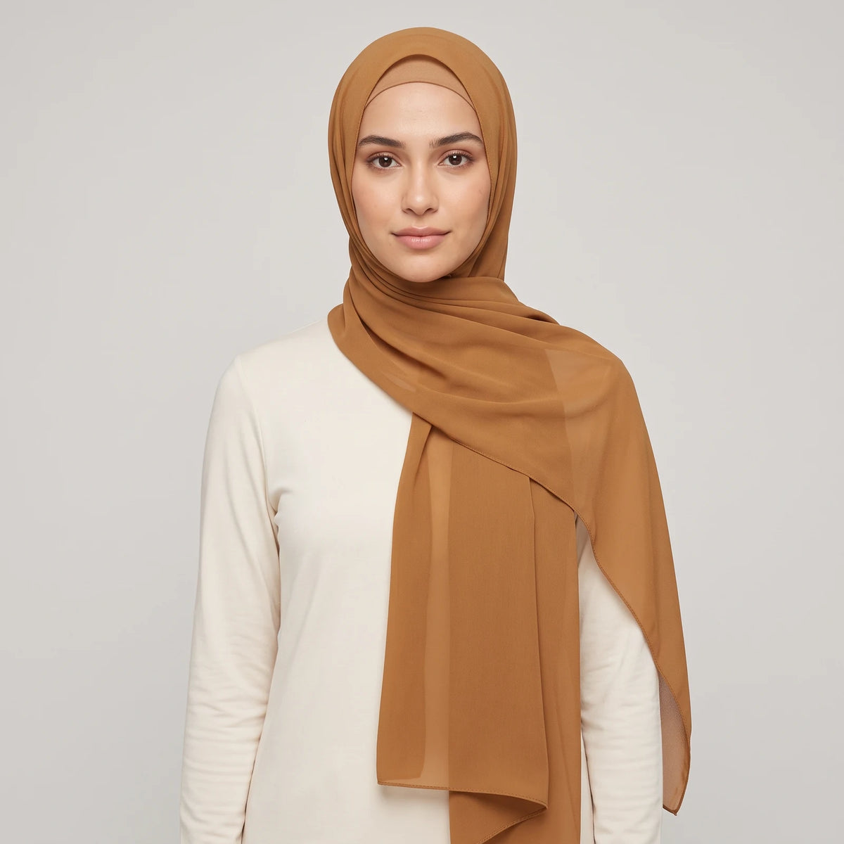 Woman wearing a gold chiffon hijab with a jersey hijab cap underneath