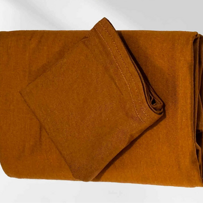 Gold jersey hijab folded with its matching hijab cap, shown as a complete set
