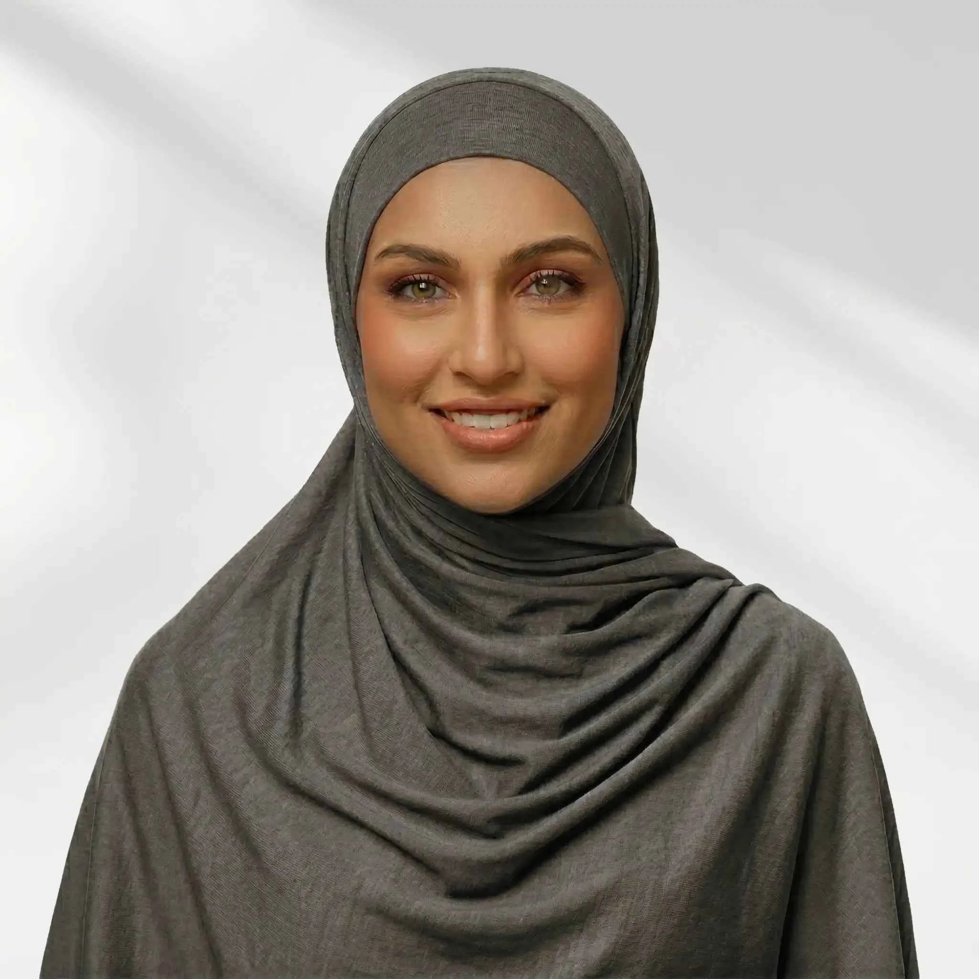 Woman wearing a gray jersey hijab draped for full chest coverage, front view