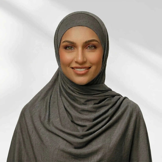 Woman wearing a gray jersey hijab draped for full chest coverage, front view
