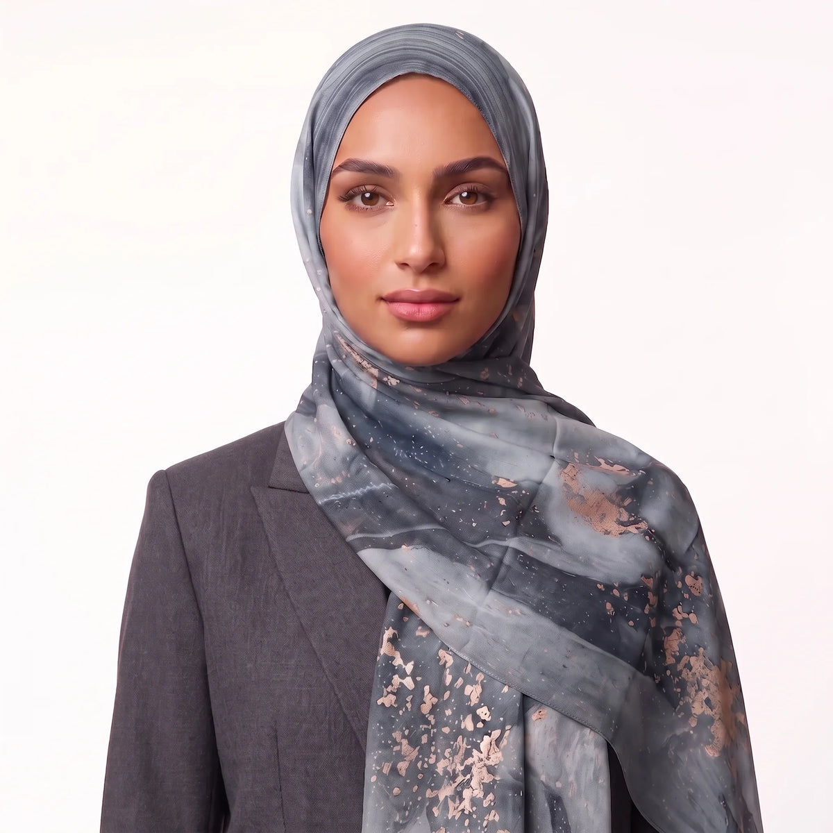 Woman wearing a grey printed hijab in modal with rose gold flecks and a charcoal blazer