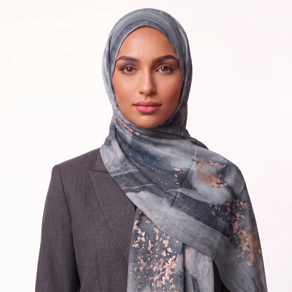 Woman wearing a grey printed hijab in modal with rose gold flecks and a charcoal blazer