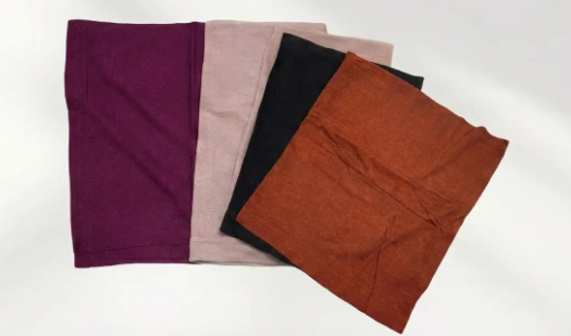 Four stretchy jersey hijab caps laid flat in purple, blush pink, black and rust, showing the tube shape and stitched edges