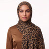 Woman wearing a leopard print modal hijab draped over the shoulder with a brown satin top