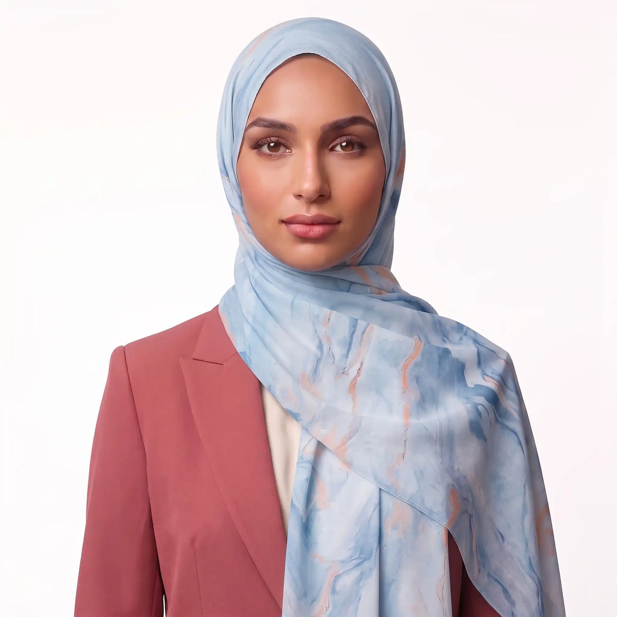 Woman wearing a light blue hijab with a marble print over a rose blazer and cream top