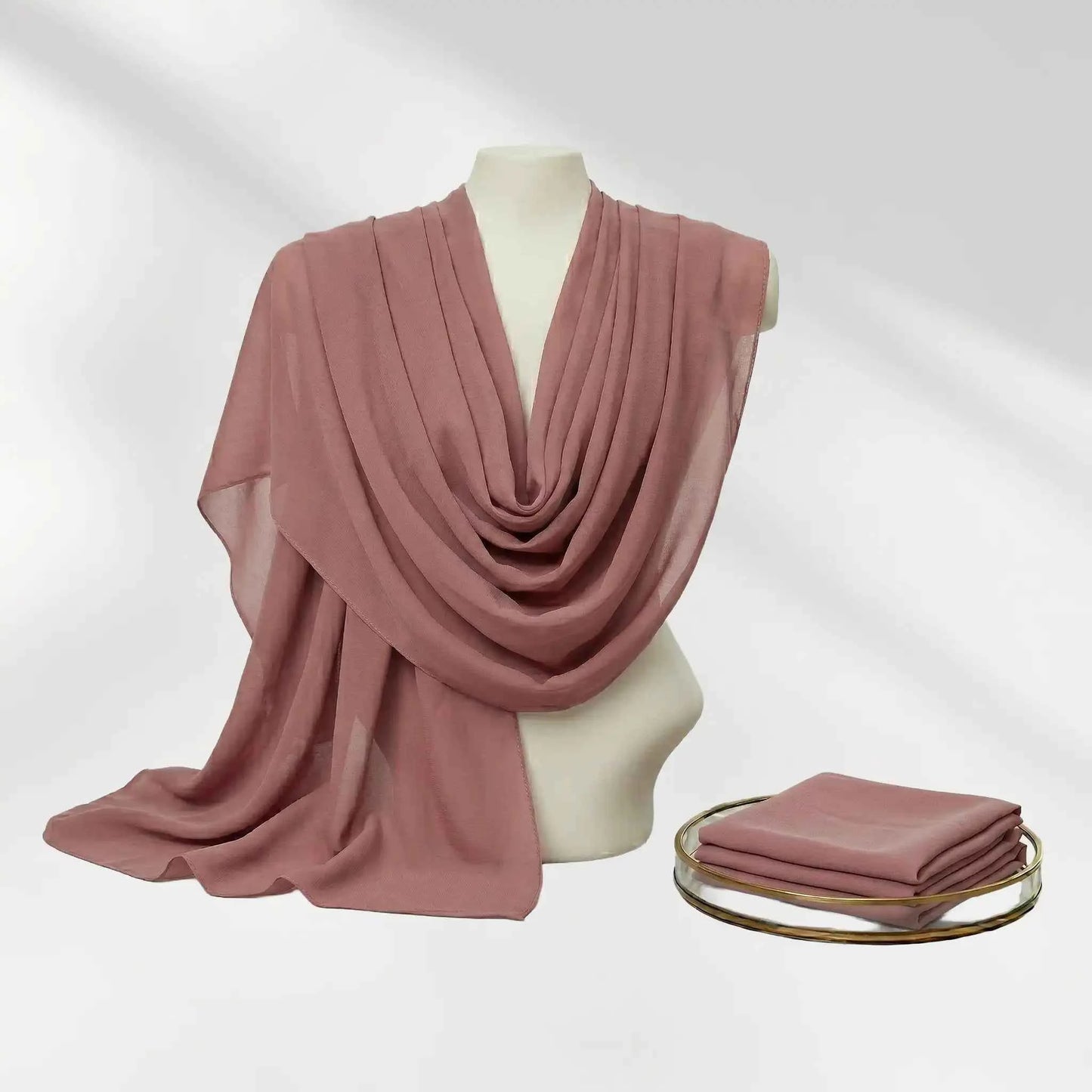 Pink chiffon hijab set draped on a mannequin bust alongside a neatly folded matching hijab scarf.