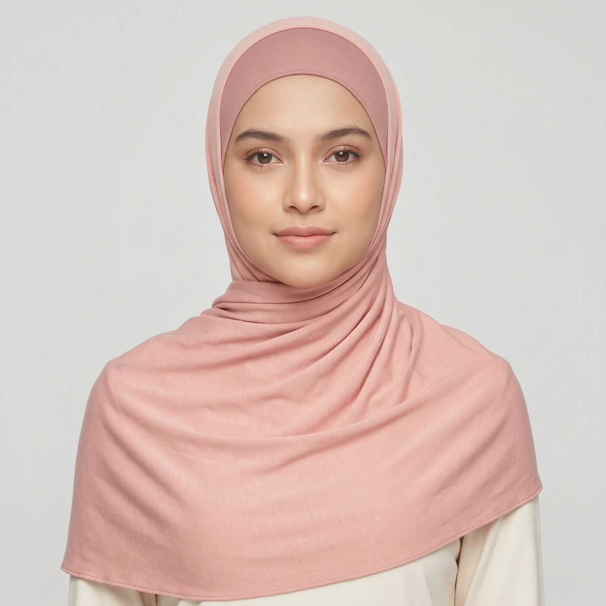 Woman wearing a light pink jersey hijab over a dusty pink hijab cap