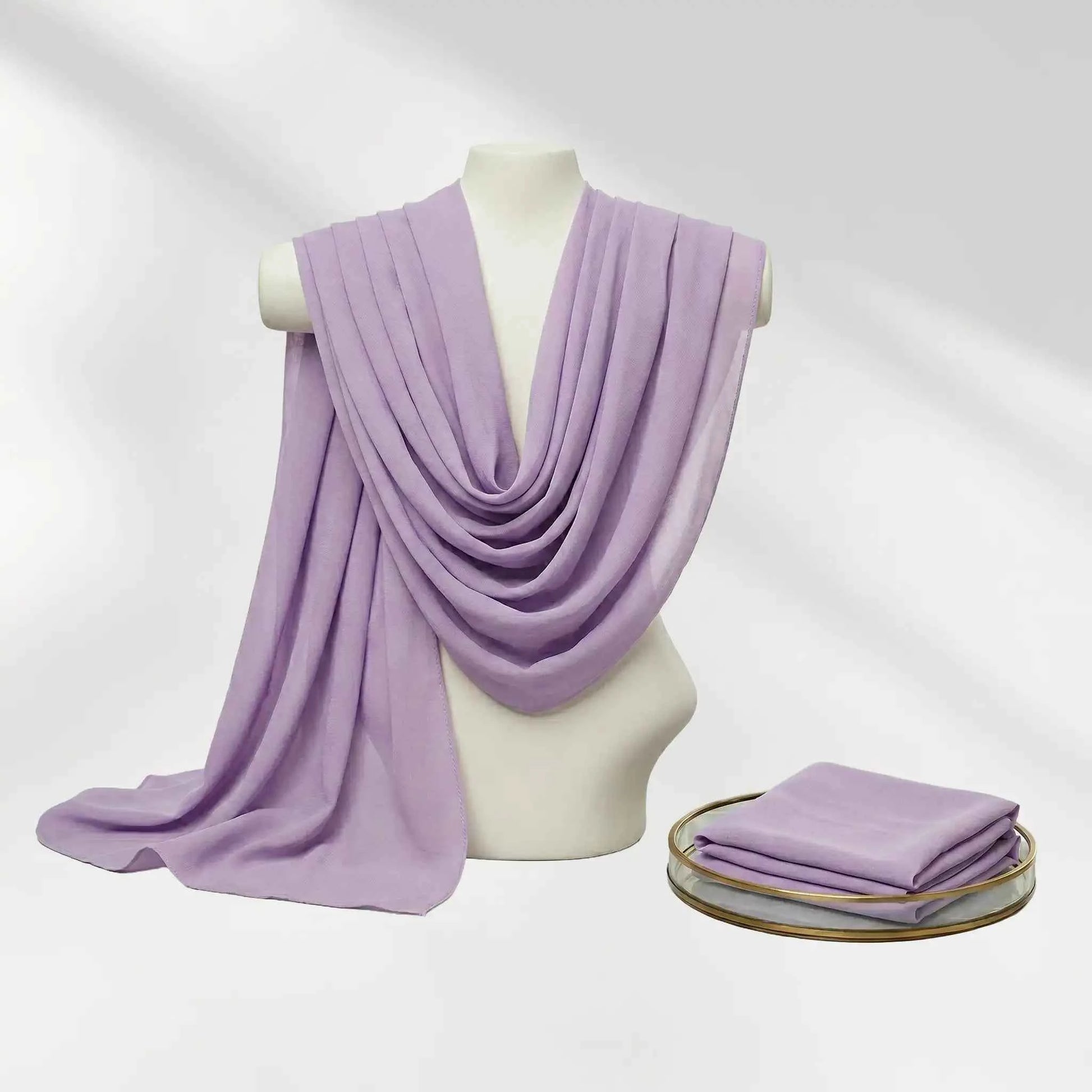 Purple chiffon hijab draped on a mannequin beside the folded scarf