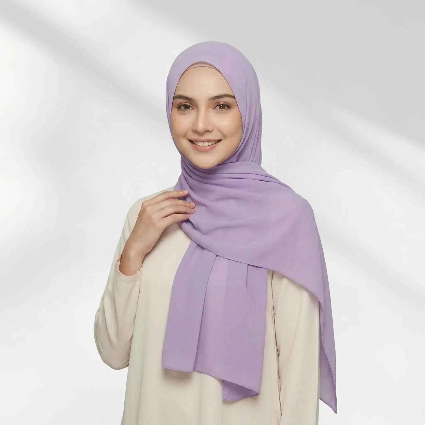 Woman wearing a purple chiffon hijab draped over one shoulder with a hijab undercap underneath