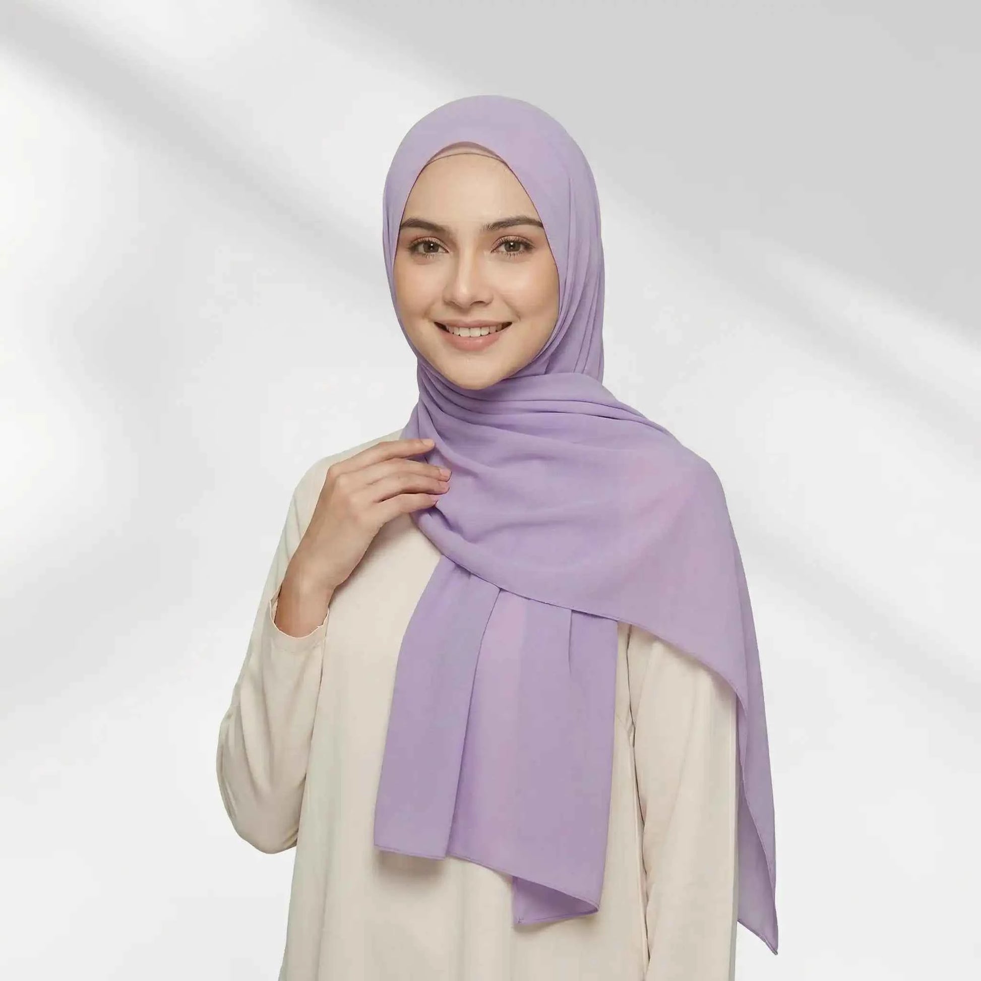 Woman wearing a purple chiffon hijab draped over one shoulder with a hijab undercap underneath