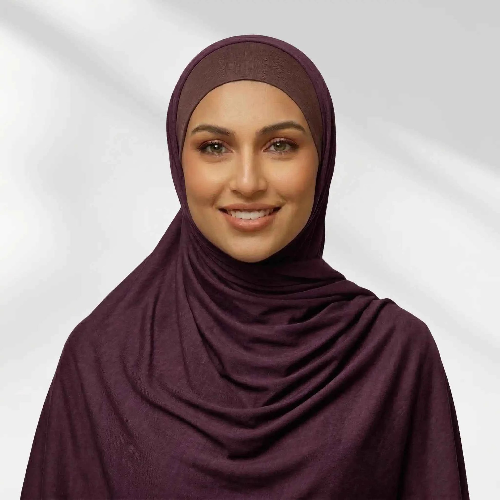 Woman wearing a purple jersey hijab in a deep plum tone, draped for full chest coverage