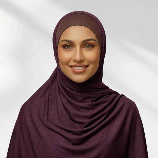 Woman wearing a purple jersey hijab in a deep plum tone, draped for full chest coverage