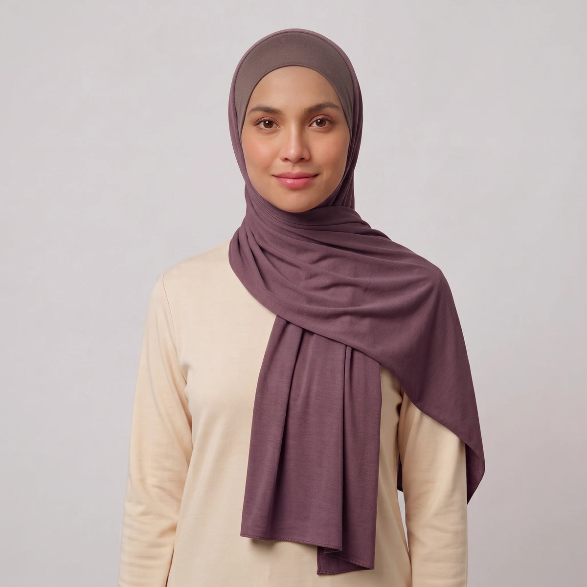 Woman wearing a purple jersey hijab over a taupe hijab cap
