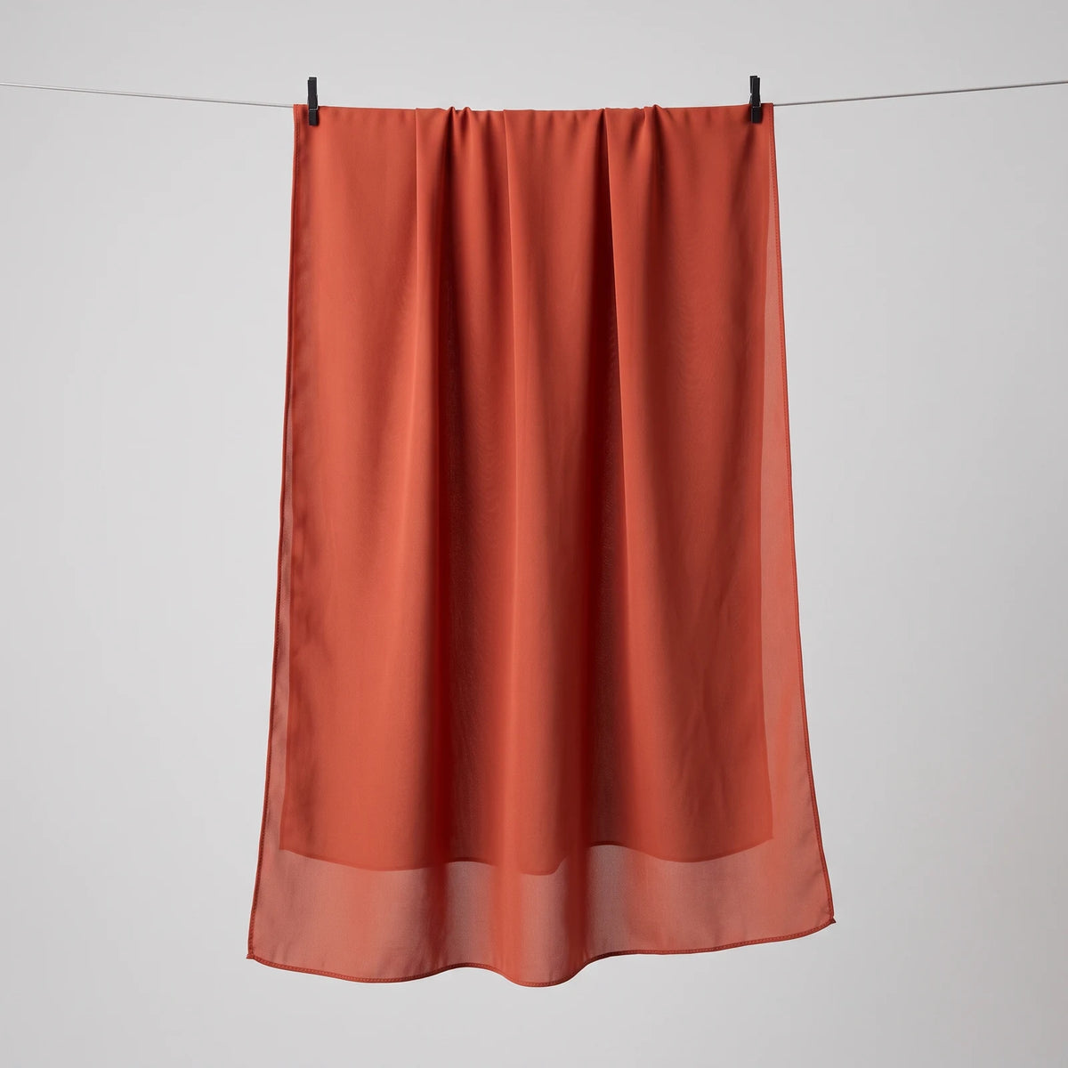 Red chiffon hijab hanging full length, showing the lightweight drape