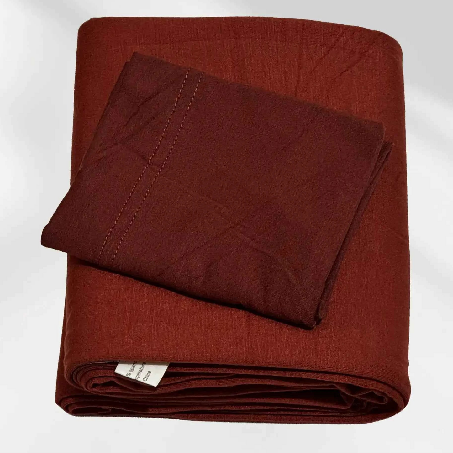 Rust red jersey hijab and matching hijab cap laid flat, showing the soft stretch fabric and stitched cap edge