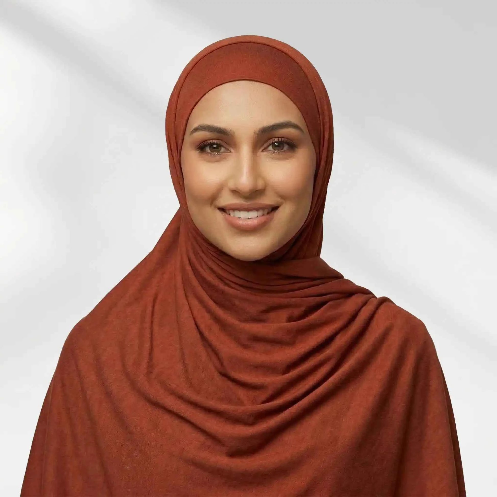 Woman wearing a rust red jersey hijab draped for full chest coverage, front view
