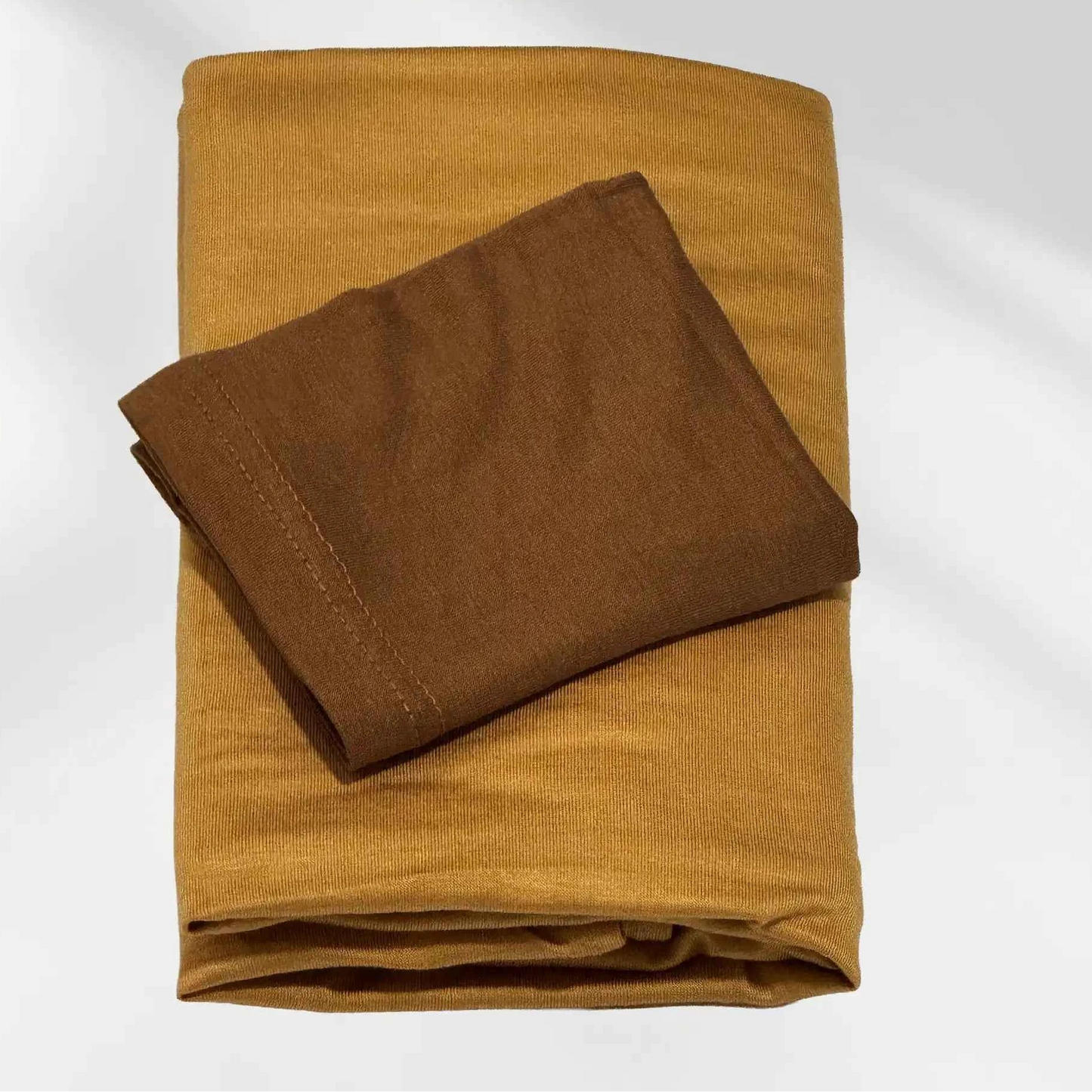 Yellow jersey hijab and brown hijab cap laid flat, showing the mustard scarf and the deeper cap shade