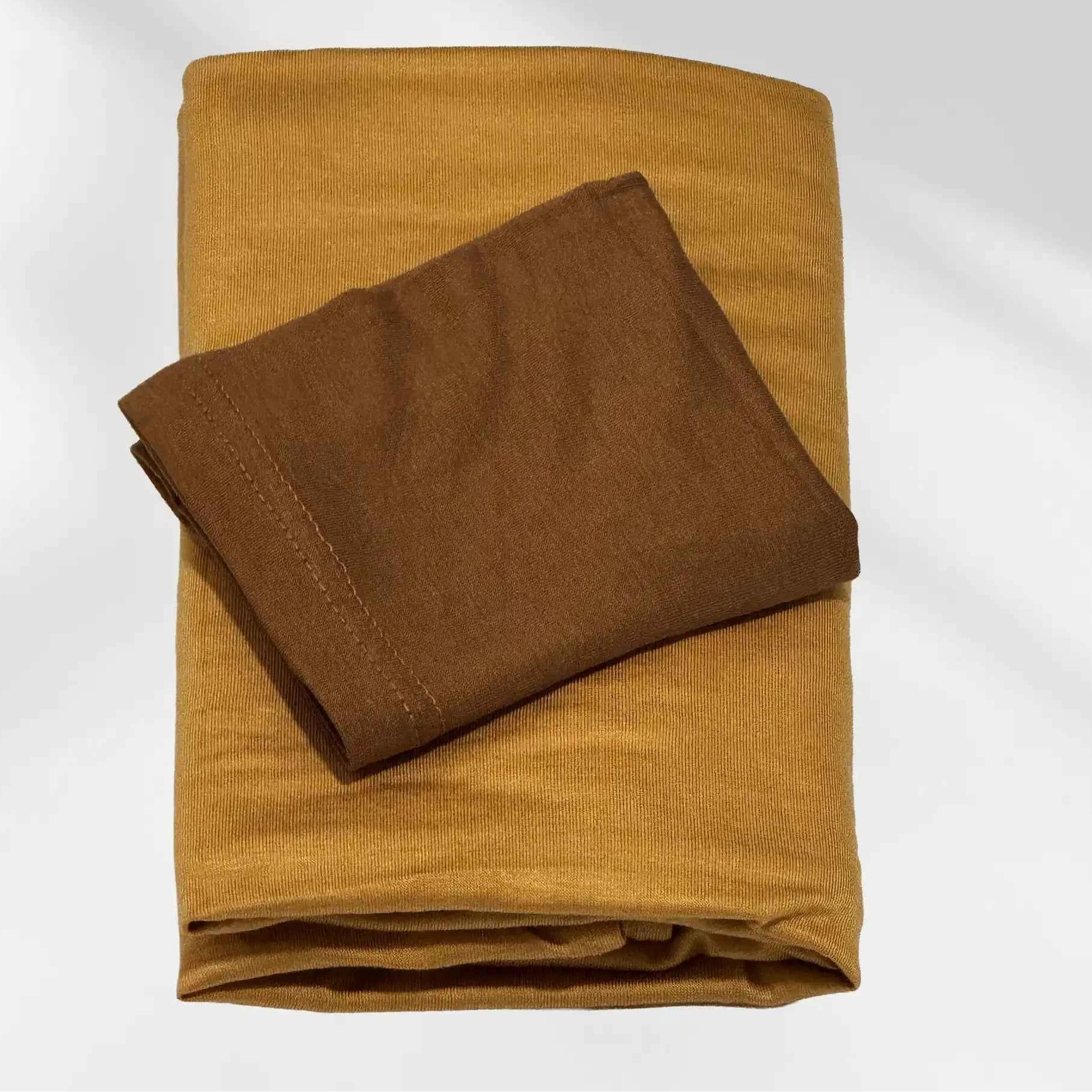 Yellow jersey hijab and brown hijab cap laid flat, showing the mustard scarf and the deeper cap shade