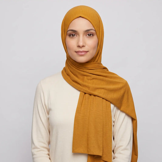 Woman wearing a yellow jersey hijab in warm gold with a cream top